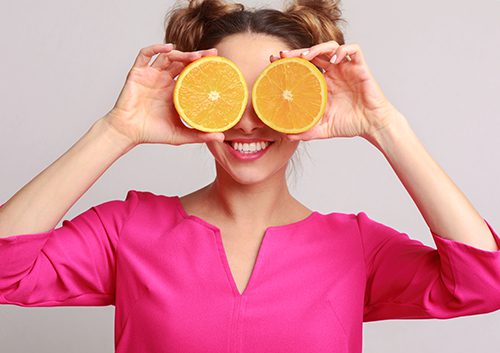Woman holding sliced orange on eye level