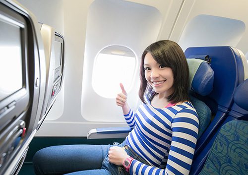 Woman on airplane doing ok sign