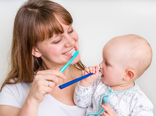 Mother and baby brushing teeth to avoid cavities