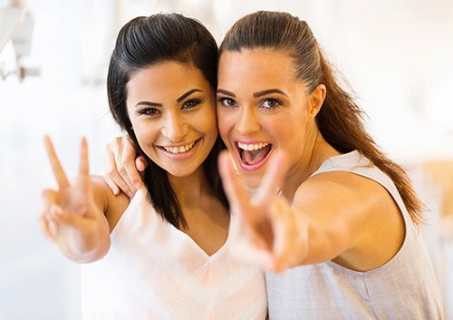 two women are showing peace sign