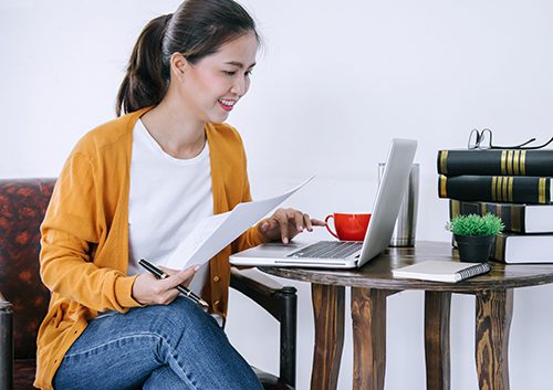 Happy casual young asian woman working in home or small office with using a laptop.