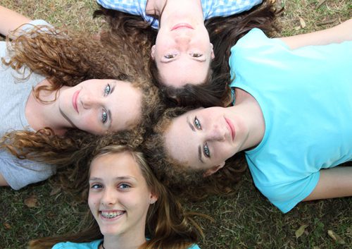 Girl teens smiling while lying on grass