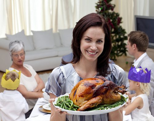 Woman smiling while holding a turkey platter for Thanksgiving
