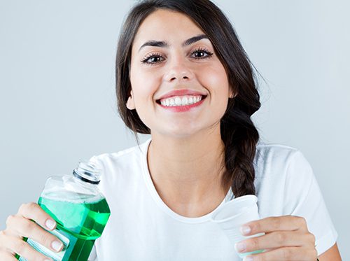 Smiling woman holding mouthwash