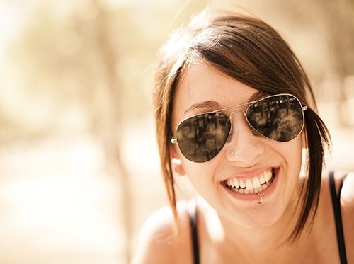 Woman with sunglasses showing her oral piercing