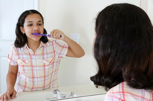 Girl brushing teeth in front of mirror