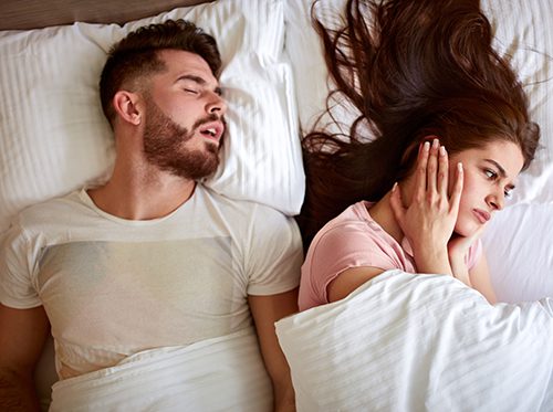 Woman covering ears due to husband snoring