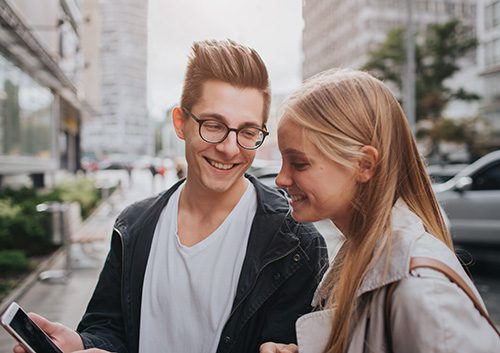 Young teens smiling while looking at cellphone