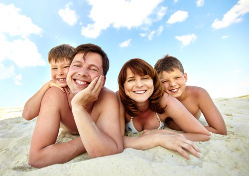 Photo of happy family lying on beach and sunbathing on summer day