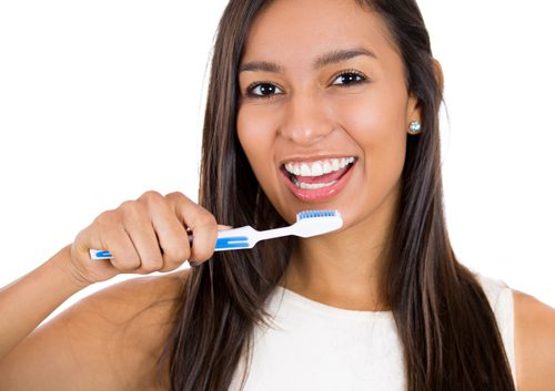 woman smiling holding a toothbrush