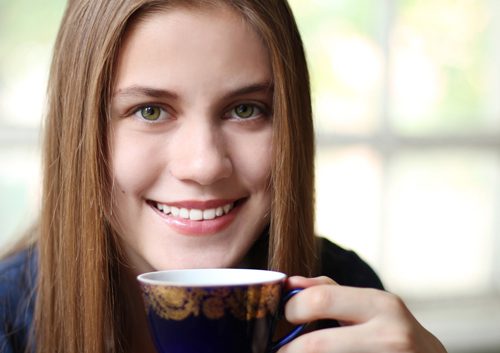 Teenage girl smiling holding a cup of coffee